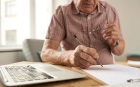 Closeup portrait of unrecognizable senior man filling in papers while working with laptop at home