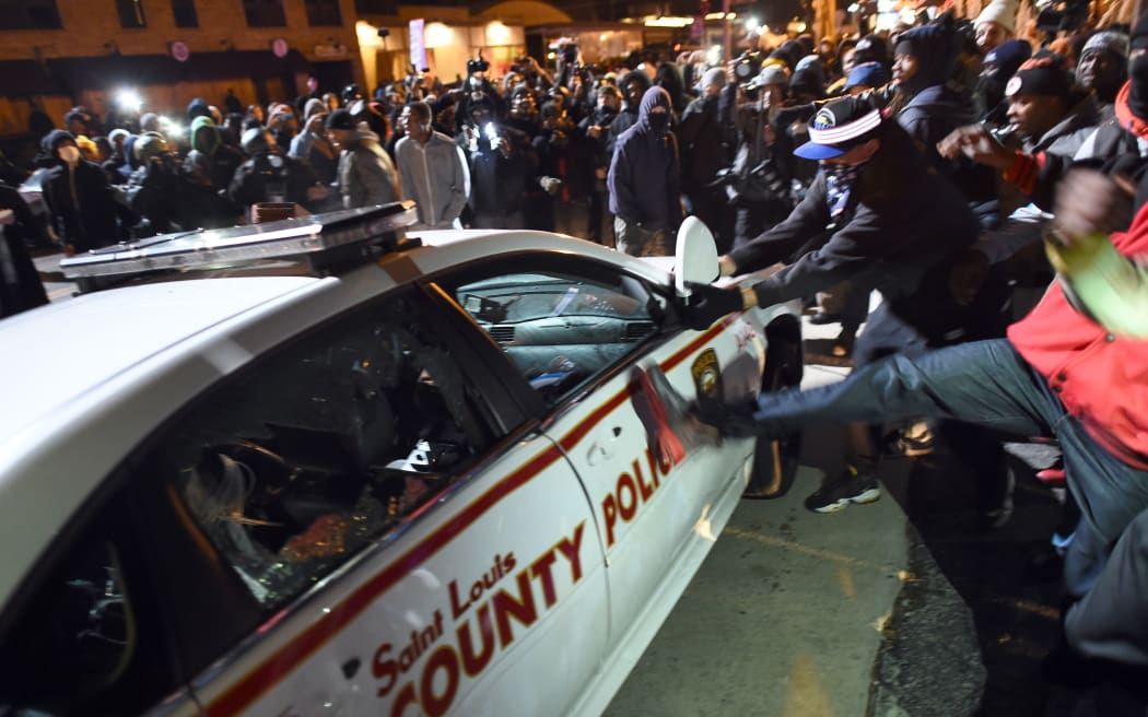 Protesters attack a police car during clashes following the grand jury decision in the death of 18-year-old Michael Brown in Ferguson, Missouri.