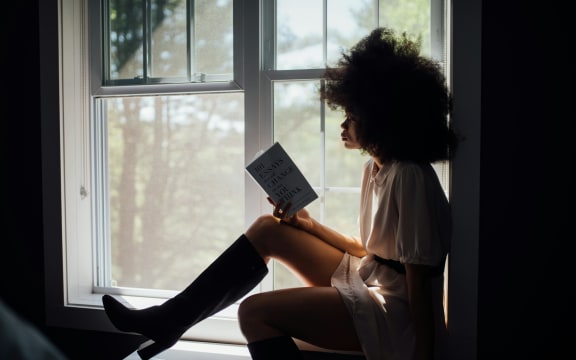 A woman reads a book in a windowsill