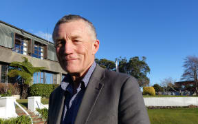 Man stands outside offices under  blue sky