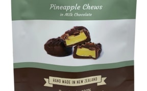 A flat-lay of a bag of confectionary. The Potter Brothers logo, a cartoonish picture of two men's faces, sits at the top. The hero image is of pineapple chews, delicately stacked on top of one another. Above, the packaging says PINEAPPLE CHEWS - IN MILK CHOCOLATE. Below, the packaging says HAND MADE IN NEW ZEALAND.