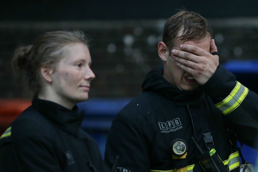 Firefighters react at the scene of the Grenfell Tower fire. About 200 firefighters are in attendance.