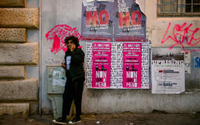A man telephones while standing in front of posters belonging to the 'No' campaign ahead of the upcoming referendum to amend the Italian constitution.