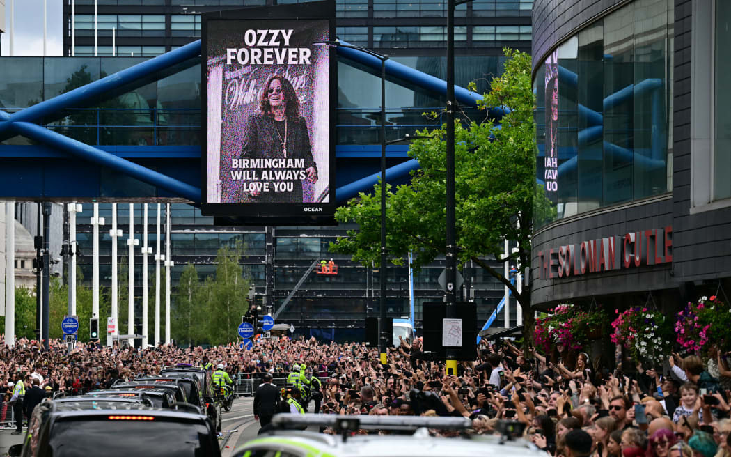 Mourners and music fans line the streets to pay their respects as the funeral cortege of Ozzy Osbourne, the late lead singer of Black Sabbath, makes its way through Birmingham, central England on July 30, 2025. Thousands are expected to line the streets in Ozzy Osbourne's UK hometown of Birmingham on Wednesday to honour the heavy metal hell-raiser Ozzy Osbourne as he is laid to rest. Osbourne, nicknamed the "Prince of Darkness" and who once bit a bat while on stage while performing with his Black Sabbath band, died on July 22 at the age of 76. (Photo by Ben STANSALL / AFP)