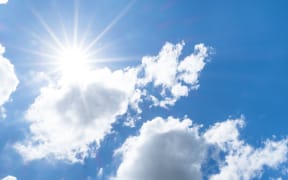 Looking up at Nice blue sky with sun beam behind big cloud.