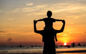 father and son on sky at sunset beach