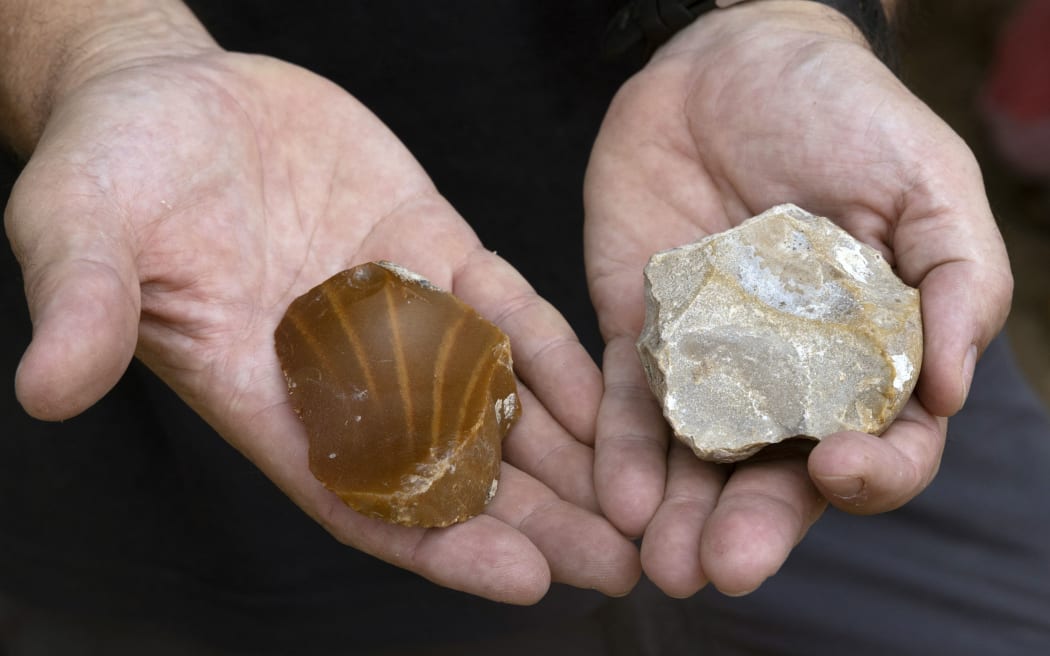Omry Barzilai of Israel Antiquities Authority, shows ancient prehistoric tools found at the site where a 2.5-meter-long tusk from an ancient straight-tusked elephant (Palaeoloxodon antiquus) was discovered, near Kibbutz Revadim in southern Israel on August 31 2022. - Dr. Eitan Mor, a biologist from Jerusalem, was the first to discover the fossil. He visited the area out of curiosity after reading about prehistoric elephants. Mor says, “To my surprise, I spotted something that looked like a large animal bone peeping out of the ground. When I looked closer, I realised that it was ‘the real thing’, so I rushed to report it to the Israel Antiquities Authority". (Photo by MENAHEM KAHANA / AFP)