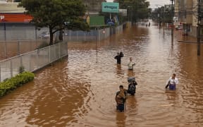 People walking through a flooded street at the Navegantes neighborhood in Porto Alegre, Brazil on 4 May, 2024.