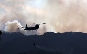 Japan Self-Defense Force helicopter collects seawater from Ofunato Port and heads to the forest fire site in Ofunato City in Iwate Prefecture, northern region of Japanese Archipelago, on March 2, 2025. The wildfire broke out on February 26th, and firefighting efforts including Japan Self-Defense Forces have continued. Approximately 4,600 people have been asked to evacuate, and about 1,000 people were taking shelter in evacuation centers. At least 84 houses and other buildings were damaged. About 1,400 hectares have burned so far, and at least 84 houses damaged.    ( The Yomiuri Shimbun ) (Photo by Hiroto Sekiguchi / Yomiuri / The Yomiuri Shimbun via AFP)