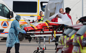 Firefighters carry an injured migrant on a stretcher after the sinking of a migrant boat attempting to cross the English Channel to England, in Boulogne-sur-Mer, northern France, on September 3, 2024. Twelve migrants died off the northern French coast on September 3 trying to cross the Channel to England, the French government said, raising an earlier death toll. Interior Minister Gerald Darmanin said on X that two migrants were still missing in the "terrible disaster" and several were injured after their boat ran into trouble, sparking a major rescue operation. (Photo by Denis Charlet / AFP)