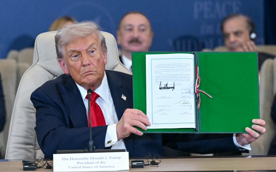 US President Donald Trump shows a signed document during a summit on Gaza in Sharm el-Sheikh on October 13, 2025. Trump landed in Egypt on October 13 for a summit on Gaza, following a lightning visit to Israel after a ceasefire he brokered entered into force. (Photo by SAUL LOEB / AFP)