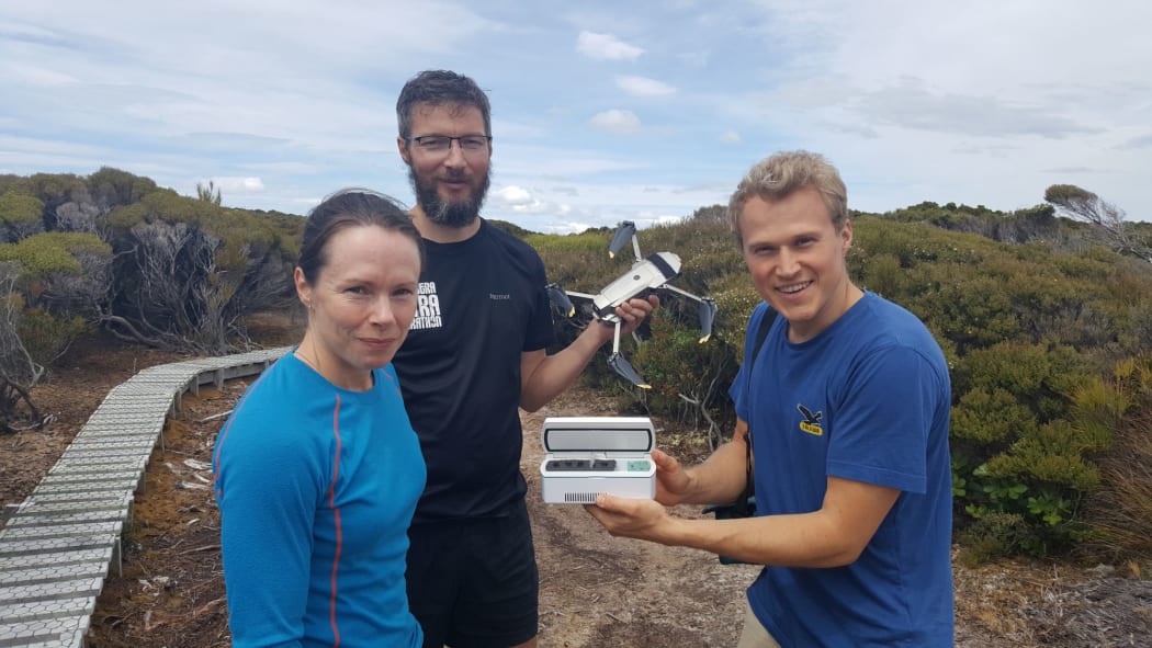 Flying kākāpō sperm - a world first. DOC's Kākāpō Recovery Team manager Deidre Vercoe with 'spermcopter' drone pilot Anton Marsden, and sperm expert Andreas Bublat holding a tiny vial of kākāpō sperm.