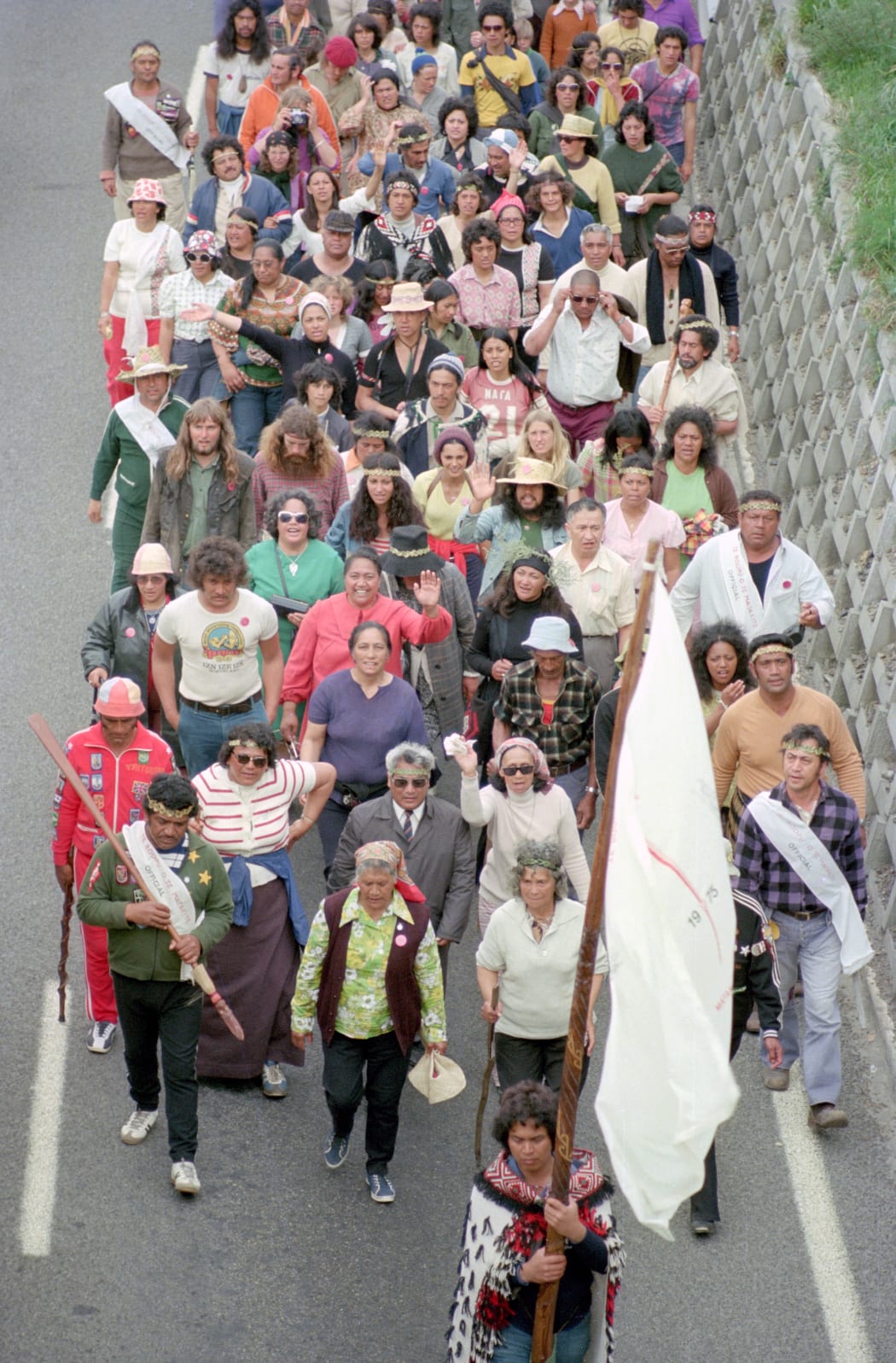 Photo of Māori Land March on Wellington motorway, 13 October 1975. Vivian Hutchinson is at left with long hair and beard, and wearing green jacket.
ATL Ref: 35mm-87561-3-F