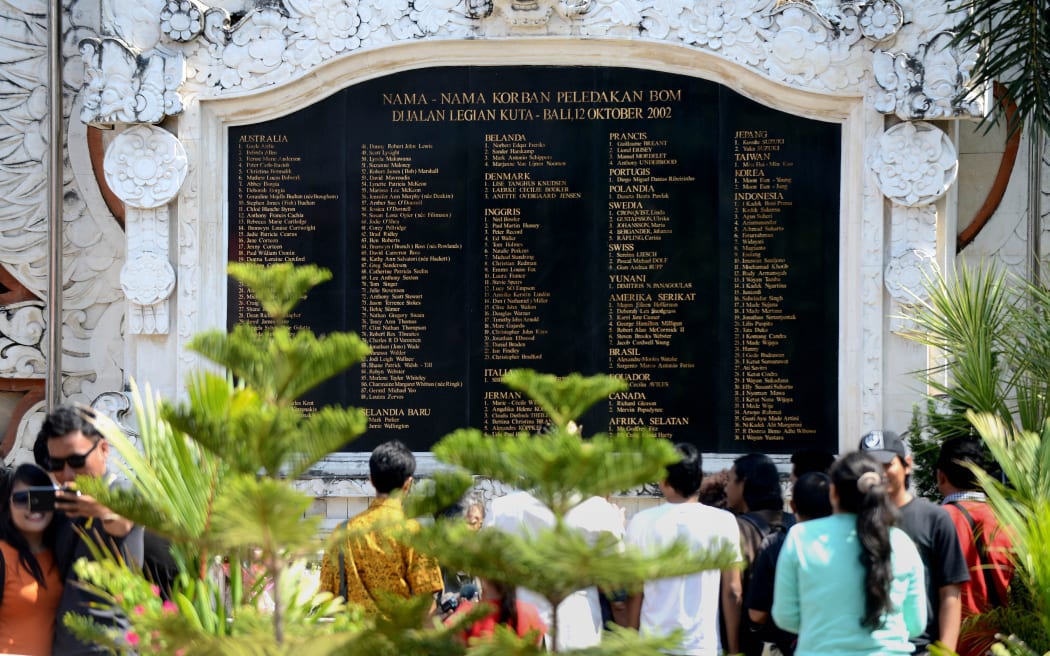 Tourists look at a large marble plaque listing the victims as they visit the Bali bombing memorial on the 13th anniversary of the 2002 blasts.
