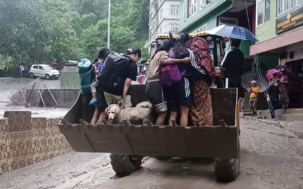 This handout photograph released by the Indian Ministry of Defence and taken on October 4, 2023, shows residents being evacuated on a backhoe loader in Muguthang, in India's Sikkim state following a flash flood caused by intense rainfall. The Indian army said October 4 that 23 soldiers were missing after a powerful flash flood caused by intense rainfall tore through a valley in the mountainous northeast Sikkim state. (Photo by INDIAN MINISTRY OF DEFENCE / AFP) / RESTRICTED TO EDITORIAL USE - MANDATORY CREDIT "AFP PHOTO / Indian Ministry of Defence- NO MARKETING NO ADVERTISING CAMPAIGNS - DISTRIBUTED AS A SERVICE TO CLIENTS