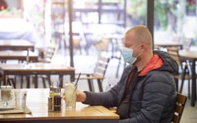 Man in restaurant wearing face mask to protect against Covid-19.