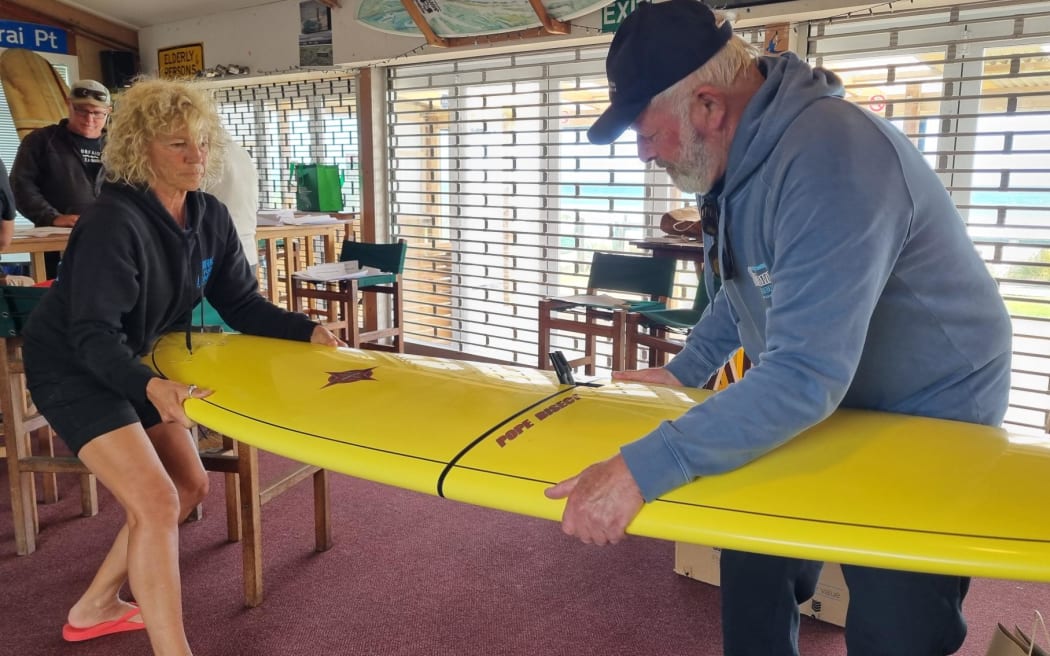 Wayne 'Arch' Arthur and Daisy Day with the curious Pope Bisect travel surfboard ... and demonstrating how it comes apart.