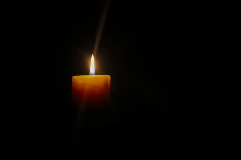 A photo of a single candle in the dark.