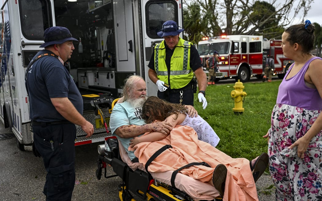 Alexa Haight hugs her grandfather Robin Haight before he is taken to the hospital by medics after getting injured by a reported tornado that hit his house in Fort Myers, Florida, on October 9, 2024, as Hurricane Milton approaches. - Florida residents fled or just hunkered down in the final hours October 9 before Milton pummels the state, as government emergency relief efforts were dragged to the center of the US election. (Photo by CHANDAN KHANNA / AFP)