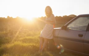 Portrait of mid adult woman leaning against car at sunset (Photo by Axel Bernstorff / Image Source / Image Source via AFP)