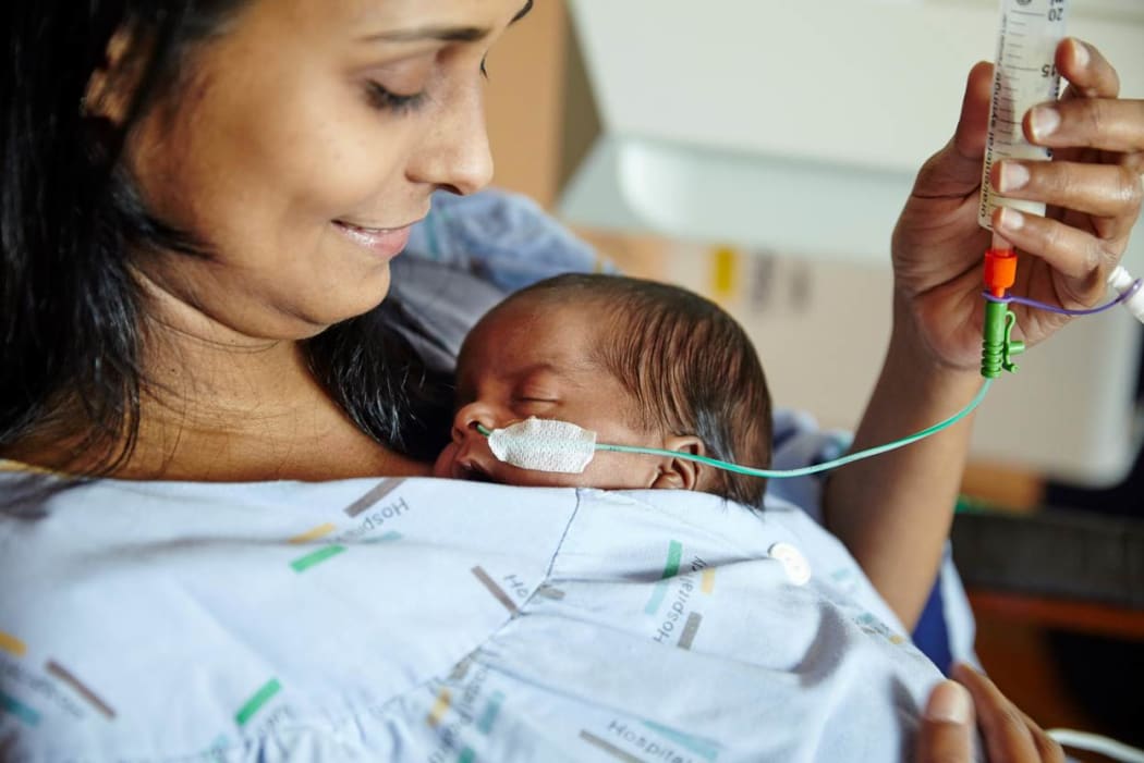 A mother tube feeds her premature baby