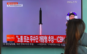 A woman walks past a television screen showing file footage of North Korea's missile launch at a railway station in Seoul on February 12, 2017.