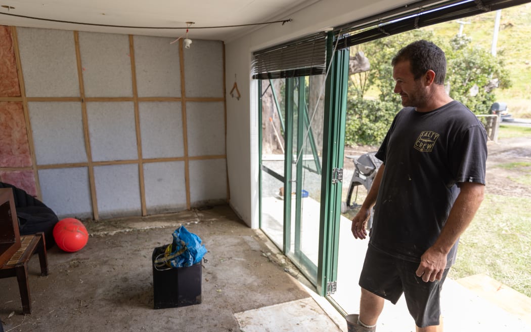 Adam Mazzola looks at damage to his home