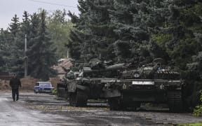 A pedestrian walks past abandoned Russian tanks in Kramatorsk, eastern Ukraine, on 1 October, 2022, amid the Russian invasion of Ukraine.