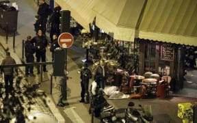 A victim lies on the ground covered by a white sheet outside a cafe, in central Paris