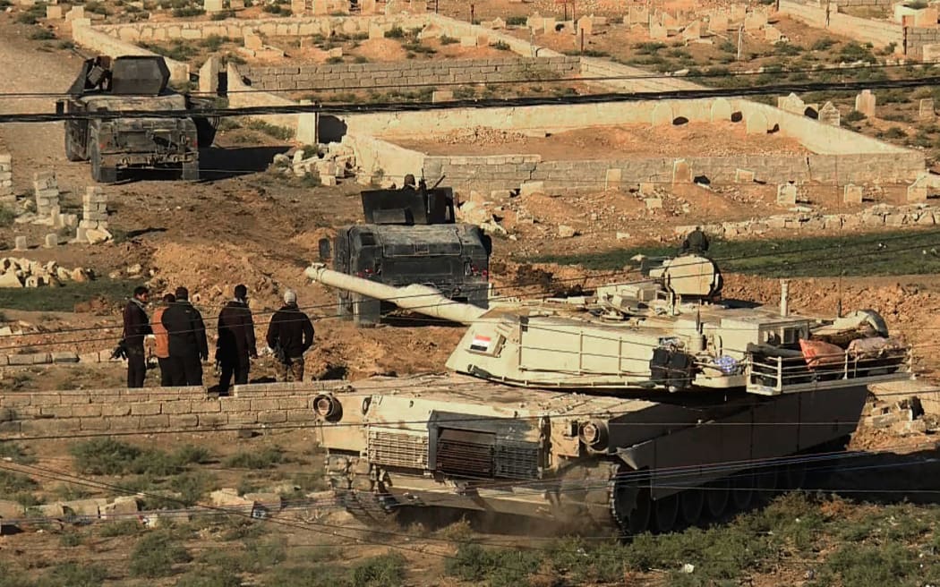An image grab taken from AFPTV shows an Iraqi forces M1 Abrams tank and armoured vehicles holding a position on the edge of the Al-Karamah district of eastern Mosul.