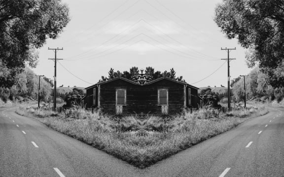 A gothic, black-and-white mirror image of a street in Whanganui featuring a ram-shackle house and powerlines.