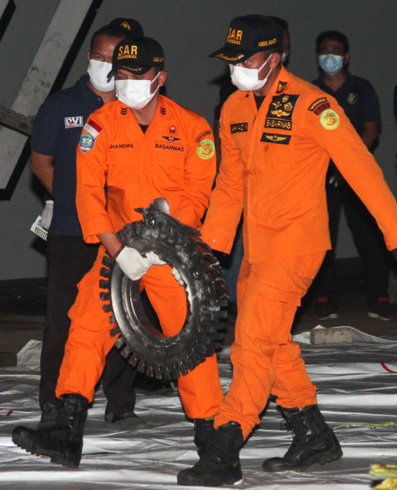Rescue personnel carry a piece of wreckage recovered from the crash site of Sriwijaya Air flight SJ182 at the port in Jakarta on January 10, 2021, following the January 9 crash of the airline's Boeing 737-500 aircraft into the Java Sea minutes after takeoff.