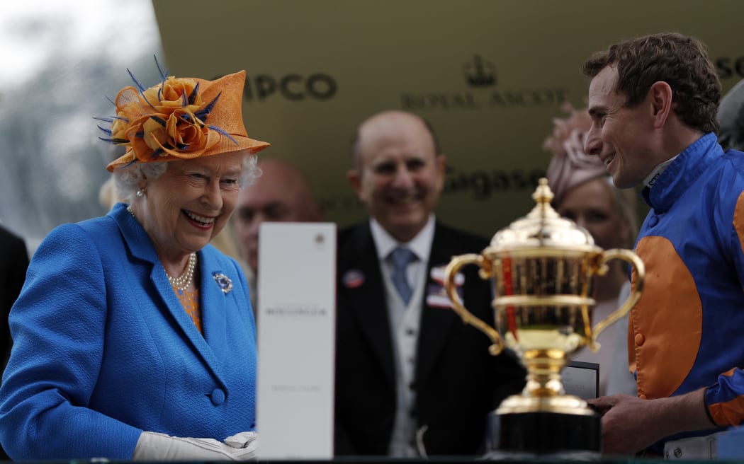 Queen Elizabeth II prepares to present jockey Ryan Moore, right, the Gold Cup after riding Order of St George win the main race during Ladies' day at Royal Ascot horse racing meet in Ascot, west of London on 16 June, 2016.
