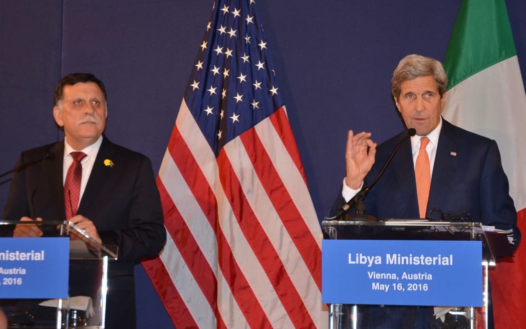 Prime Minister of Libya Fayez al-Sarraj  stands by as US Secretary of State John Kerry delivers a speech after the ministerial meeting on Libya in Vienna, Austria.