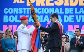 Venezuela's President Nicolas Maduro (right) receives a Venezuelan flag from a Military Commander in front of Miraflores presidential palace in Caracas on 10 January, 2025.