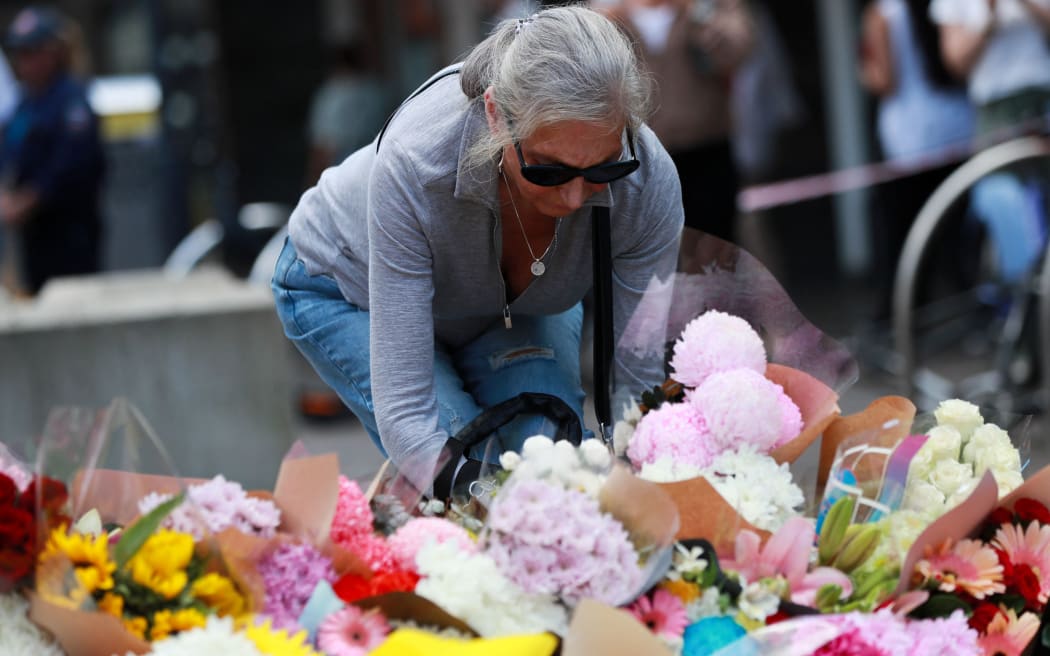 (240414) -- SYDNEY, April 14, 2024 (Xinhua) -- A woman lays flowers outside the Westfield Shopping Centre at Bondi Junction in Sydney, Australia, April 14, 2024. One Chinese citizen was killed and another wounded in a mass stabbing attack at a Sydney shopping center, the Chinese Consulate General in Sydney said on Sunday. (Xinhua/Ma Ping) (Photo by MA PING / XINHUA / Xinhua via AFP)