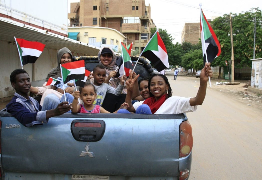 Sudanese children wave small national flags as people celebrate outside the Friendship Hall in the capital Khartoum