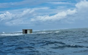 Three shipping containers floating in the sea near the sunken Manawanui ship.