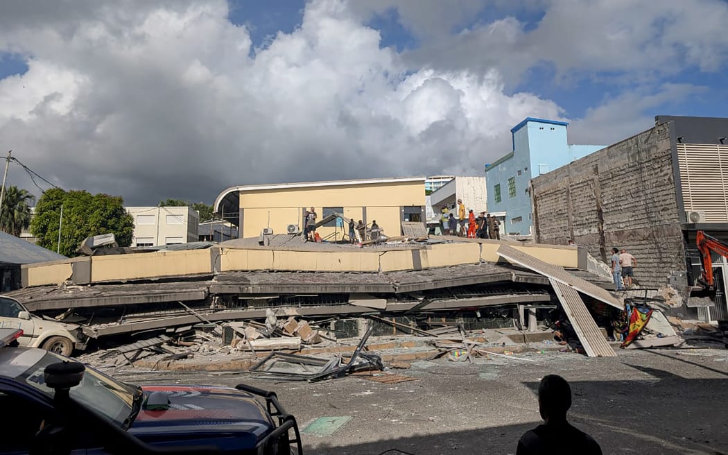 Rescue workers are seen at the site of a collapsed building after a powerful earthquake struck Port Vila, the capital city of Vanuatu, on December 17, 2024. - A powerful earthquake hit the Pacific island of Vanuatu on December 17, smashing buildings in the capital Port Vila including one housing the US and other embassies, with a witness telling AFP of bodies seen in the city. (Photo by AFP)