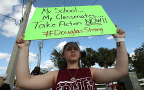 Student Angelia Lazo holds up a sign while standing near the Marjory Stoneman Douglas High School where 17 people were killed.