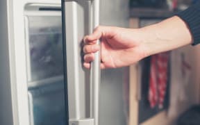 The hand of a young man is opening a freezer door