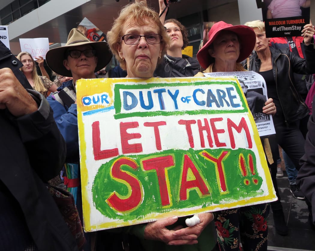 People hold up placards at a protest outside an immigration office in Sydney on February 4, 2016.