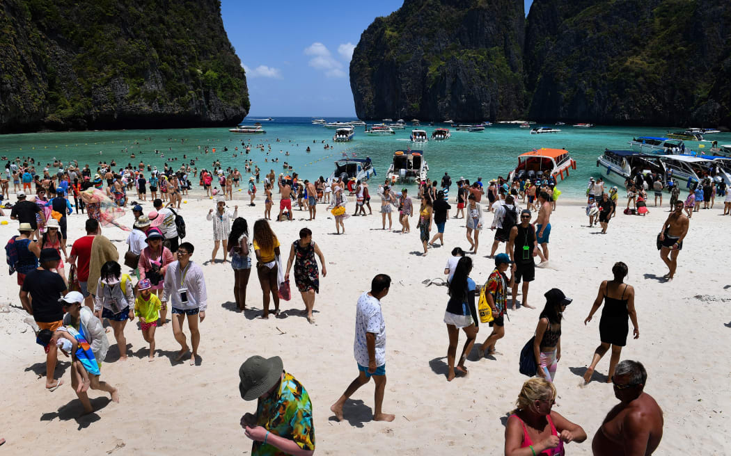 A crowd of tourists on the Maya Bay beach on 9 April 2018, on the southern Thai island of Koh Phi Phi. - Across the region, Southeast Asia's once-pristine beaches are reeling from decades of unchecked tourism as governments scramble to confront trash-filled waters and environmental degradation without puncturing a key economic driver. (Photo by Lillian SUWANRUMPHA / AFP) / TO GO WITH AFP STORY "THAILAND-INDONESIA-PHILIPPINES-TOURISM-ENVIRONMENT" by Lillian SUWANRUMPHA with Joe FREEMAN