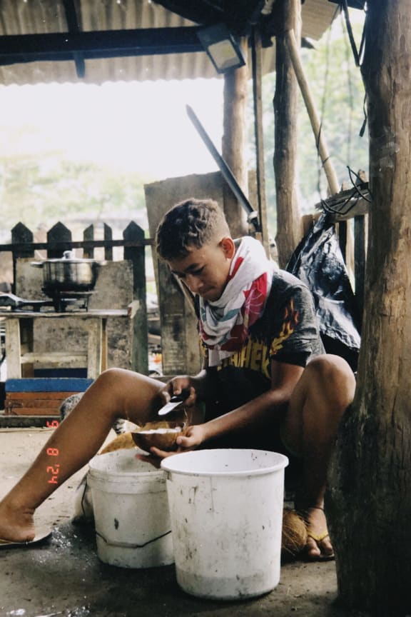 Pacific Way winner in the Our Climate, Our Future photography competition. Boy cutting and grating a coconut or "sali le popo". Samoa 2024