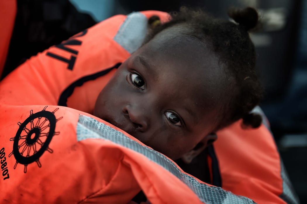 child from African origin looks on as she is rescued from a distressed vessel by a member of Proactiva Open Arms NGO in the mediteranean sea some 20 nautical miles north of Libya on October 3, 2016.