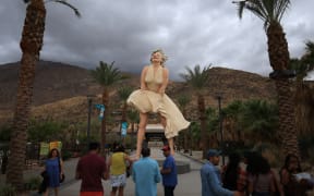 People visit the "Forever Marilyn" statue, designed by US artist John Seward Johnson II, framed by storm clouds as Hurricane Hilary heads north toward southern California, in Palm Springs, California, on August 19, 2023. Hilary brought heavy rains on August 19 to portions of Mexico's Baja California peninsula and the southwestern United States, as officials warned the powerful hurricane was likely to cause "catastrophic and life-threatening" flooding. (Photo by DAVID SWANSON / AFP) / RESTRICTED TO EDITORIAL USE - MANDATORY MENTION OF THE ARTIST UPON PUBLICATION - TO ILLUSTRATE THE EVENT AS SPECIFIED IN THE CAPTION