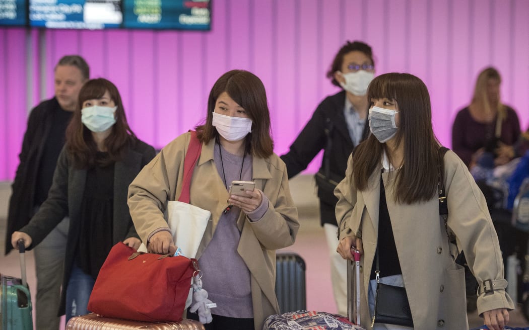 Passengers wear protective masks to protect against the spread of the Coronavirus as they arrive at the Los Angeles International Airport.