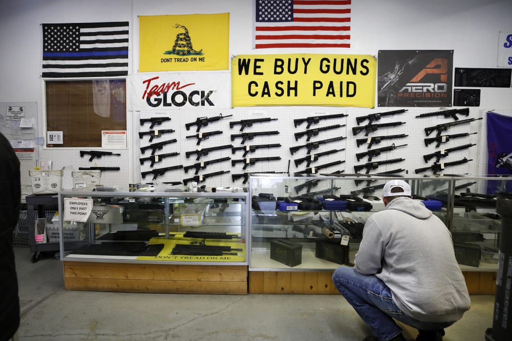 A customer looks at handguns in a case as AR-15 style rifles hang on a wall at a Utah gun store. US gun merchants sold more than 2 million firearms in January 2021, a 75 percent increase on January 2020, according to the National Shooting Sports Federation.