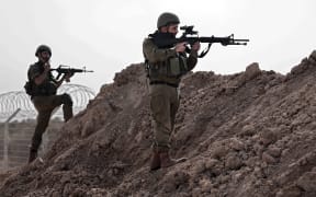 In this picture taken during a media tour organised by the Israeli military on October 22, 2023, Israeli soldiers take a defensive position in Kibbutz Beeri along the border with the Gaza Strip, in the aftermath of a Palestinian militant attack on October 7. (Photo by Thomas COEX / AFP)