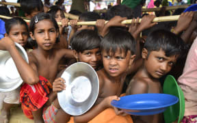 Rohingya refugee children wait to collect food at the Palongkhali makeshift Camp in Cox's Bazar, Bangladesh.
